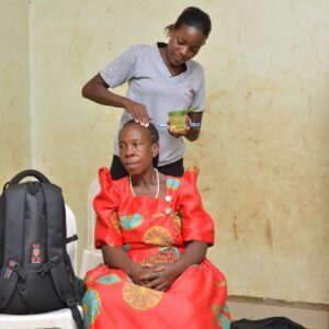 Young lady oiling an elderly woman's head hair.